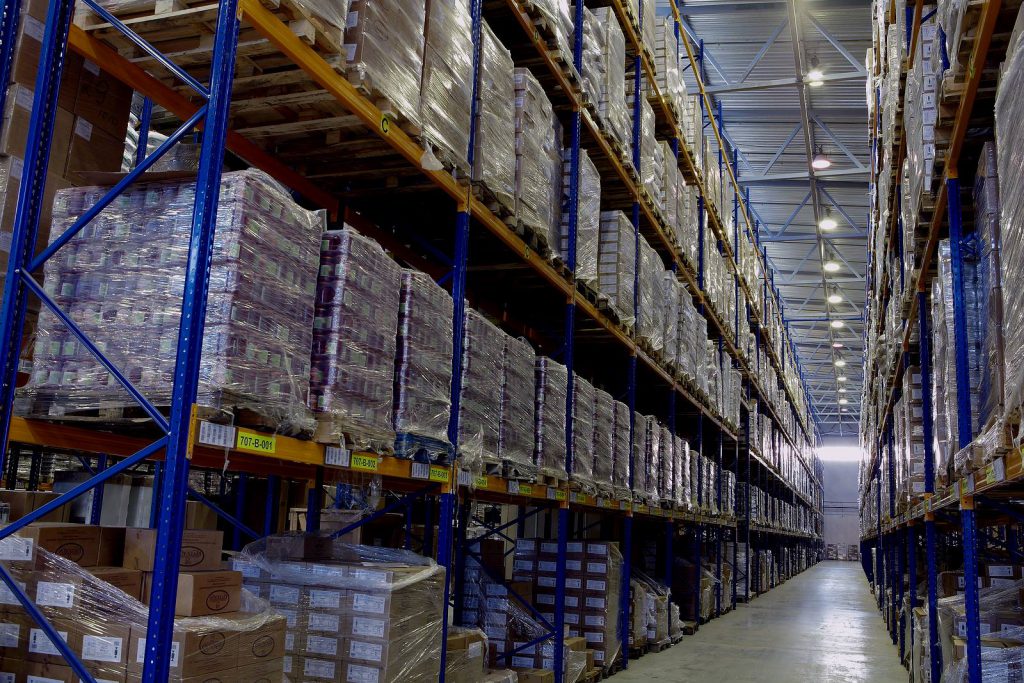 A warehouse stocked with pallets on industrial storage shelves. Controlling warehouse inventory is a vital part of supply chain management.