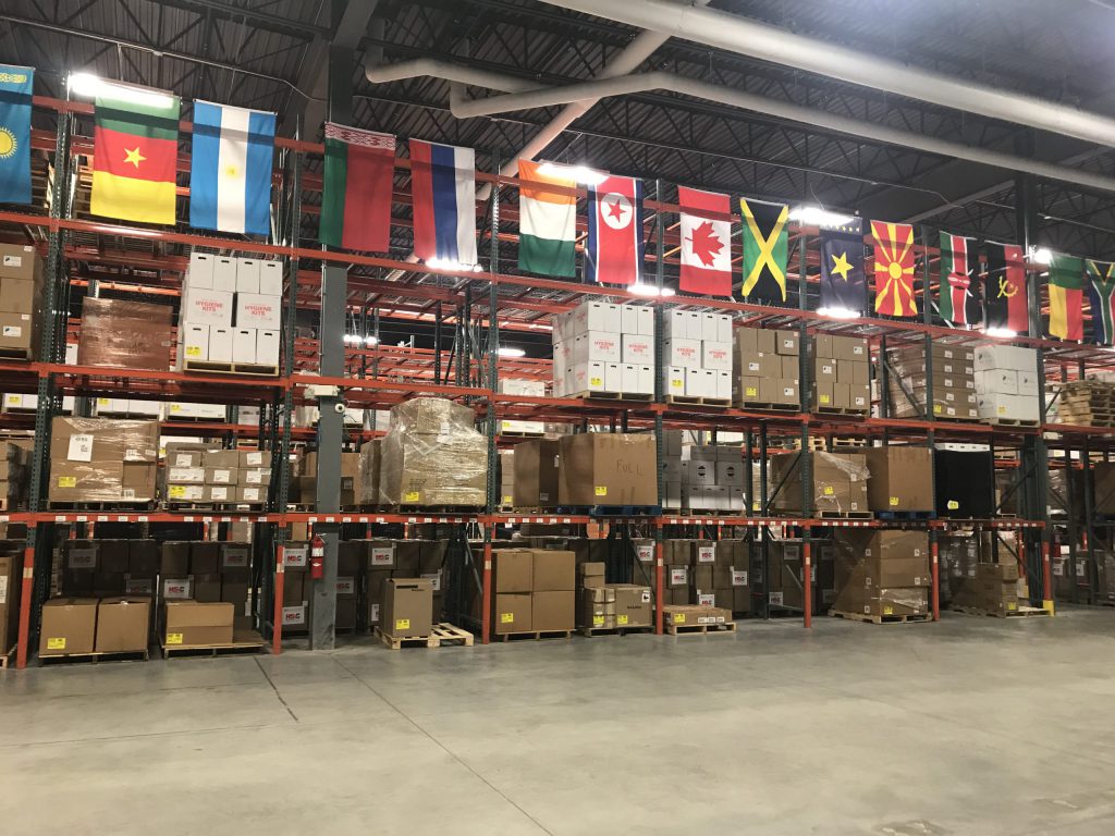 A well-stocked, well-managed, and organized warehouse with flags representing different countries hanging from the cieling.