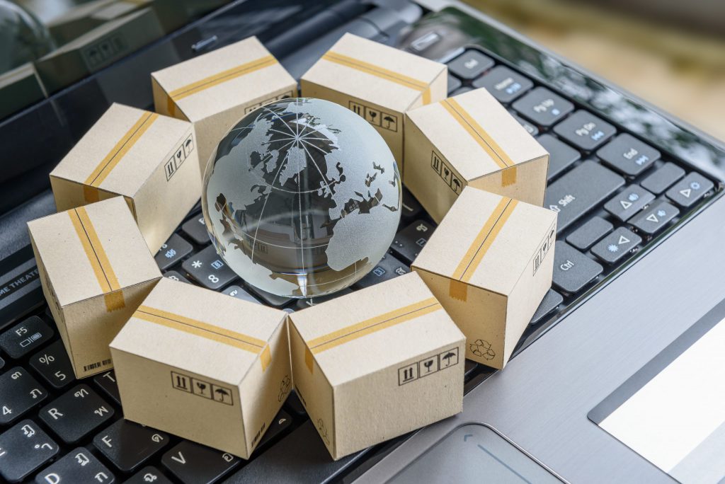 A globe surrounded by shipping boxes on a keyboard, symbolizing the logistics software offered by Humanitarian Software.